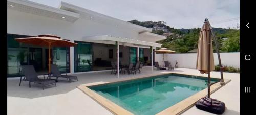 a house with a swimming pool and an umbrella at Kadena Villa in Ban Lamai