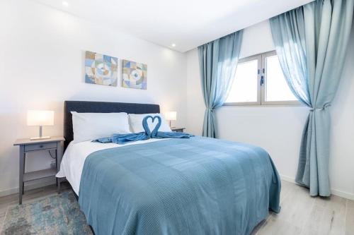 a bedroom with a bed with a blue blanket and a window at The Hub central apartment Burgau in Burgau