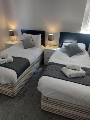 two beds in a bedroom with two lamps on tables at The Sanderling in Morecambe