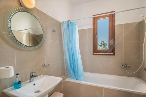 bagno con lavandino, vasca e specchio di Ciel Blue Villas a Kiotari
