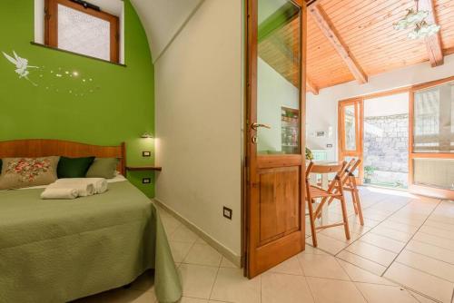 um quarto com paredes verdes, uma cama e uma mesa em [Sorrento Coast] Villa with garden Il Glicine em Piano di Sorrento