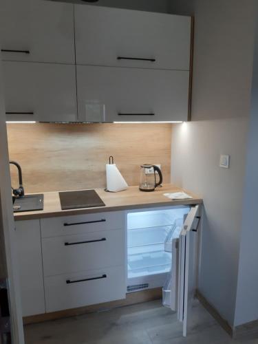 a kitchen with white cabinets and an open refrigerator at Apartamenty nad Strumykiem in Brenna