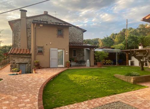 a house with a brick driveway and a lawn at Calema Country House Vinci in Vinci