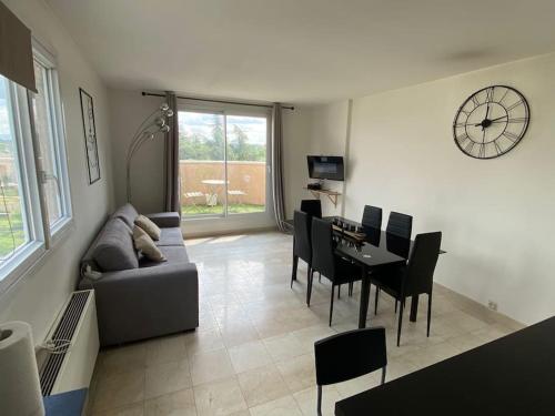 a living room with a couch and a table and a clock at Belle vue de Lognes- 15min Disney/ 5min gare / Parking gratuit in Lognes