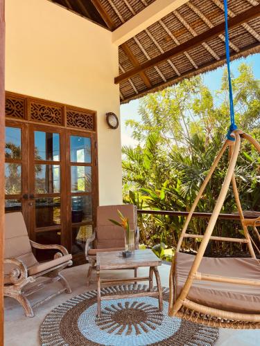 a porch with a swing and a table at Two Smiling Buddhas in Jasri