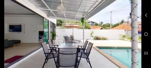 a dining room with a table and chairs next to a swimming pool at kadena villa in Koh Samui 
