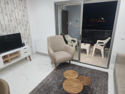 a living room with a tv and a chair and a table at Sublime appartement le Palace Hammamet Nord Mrezga - Family only in Hammamet