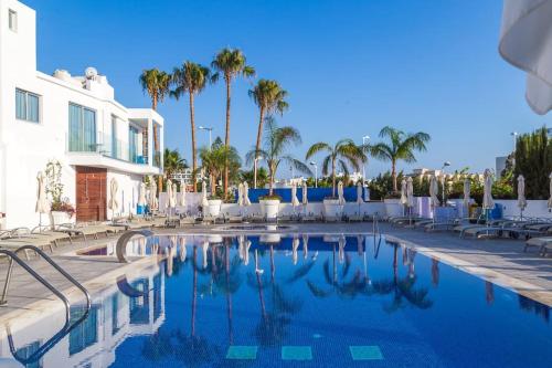a swimming pool with chairs and palm trees at Fig Tree Island Apartment-144 in Protaras