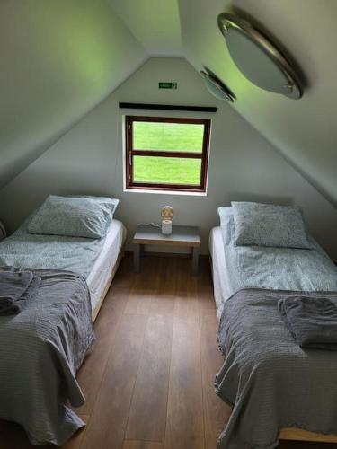 a attic bedroom with two beds and a window at Hólar Countryside Cabin 2 in Selfoss