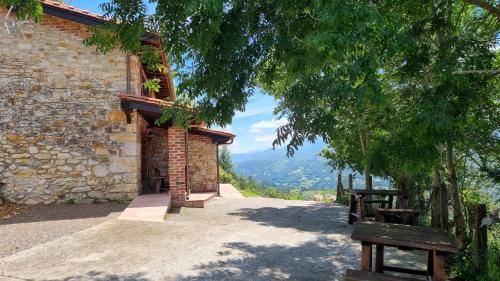 un edificio de piedra con dos bancos en un camino en Apartamentos La Cabaña del Cerro Alto, en Beceña