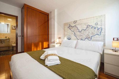 a bedroom with a white bed with a map on the wall at Piles Garden Apartamento in Gijón