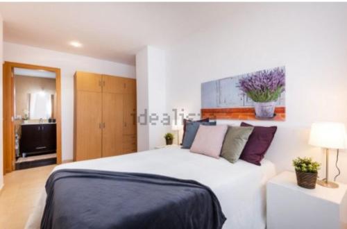 a bedroom with a large white bed with purple pillows at Vacaciones perfectas. in Paterna