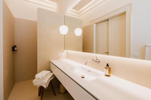 a white bathroom with a sink and a mirror at Das Edith in Stuttgart