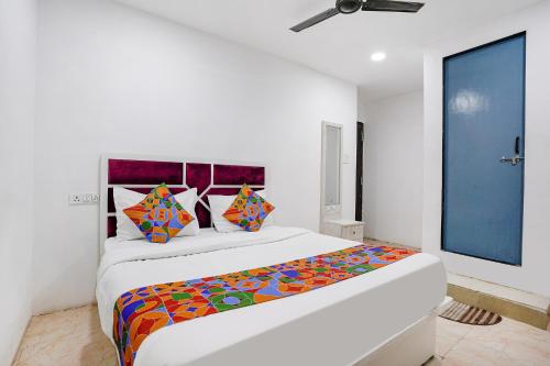 a white bedroom with a large bed with colorful pillows at FabExpress VYS Inn in Pune