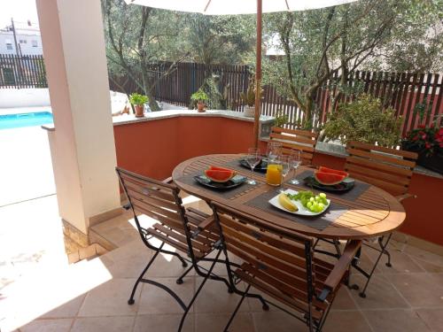 a table and chairs on a patio with an umbrella at Apartment Kućica in Zadar