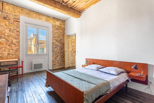 a bedroom with a bed and a brick wall at 70’s flat in Toulon