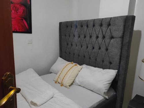 a bed with white pillows and a gray headboard at Immaculate 1-Bed Apartment in Nairobi in Nairobi