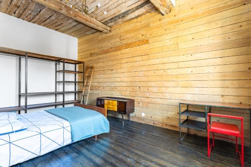 - une chambre avec un mur en bois, un lit et un bureau dans l'établissement T3 charme ancien au coeur de Toulon, à Toulon
