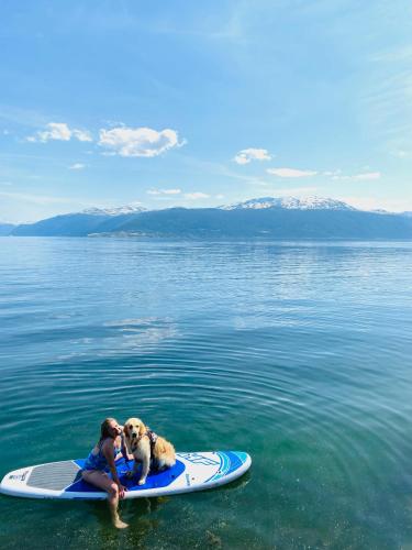 a woman and a dog on a surfboard in the water at Balestrand Hotel in Balestrand