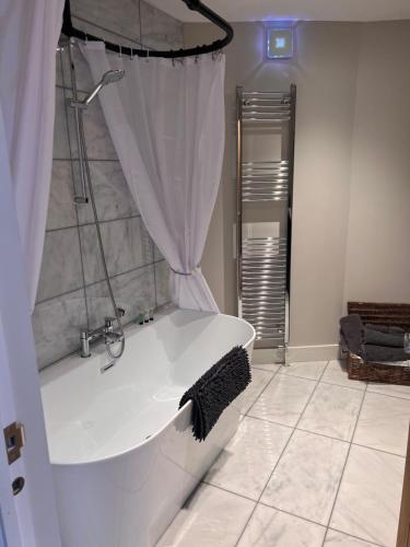 a white bath tub in a bathroom with a shower at Cosy newly renovated 3 bedroom house - Town centre Horncastle in Lincolnshire