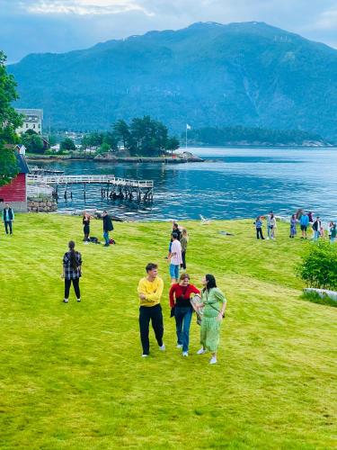 a group of people walking on the grass near a body of water at Balestrand Hotel in Balestrand