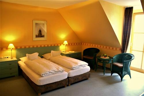 a bedroom with two beds and chairs in a room at Hotel-Restaurant Zum Landgraf in Wartmannsroth