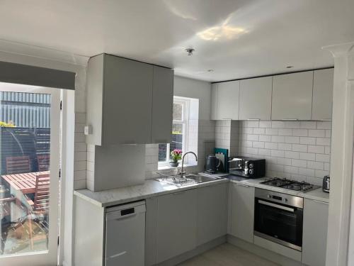 a white kitchen with a sink and a stove at Bright one bed apartment with free parking in Brighton & Hove