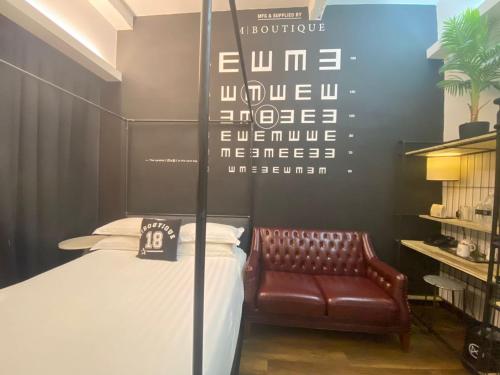 a bedroom with a bed and a leather chair at M Boutique Hotel Station 18 - Ipoh in Ipoh