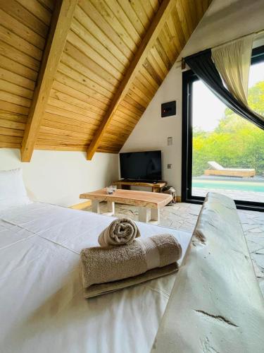 a bedroom with a white bed with a large window at Unique wooden villa with pool in Olympiada