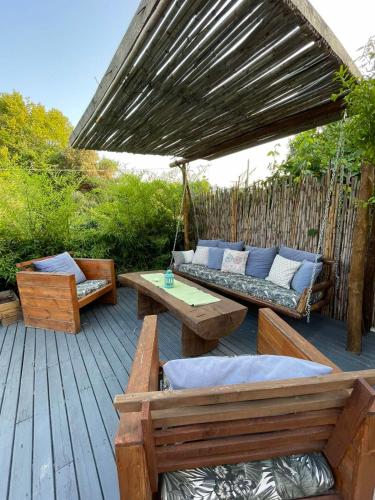 a patio with a hammock and a couch and tables at Unique wooden villa with pool in Olympiada
