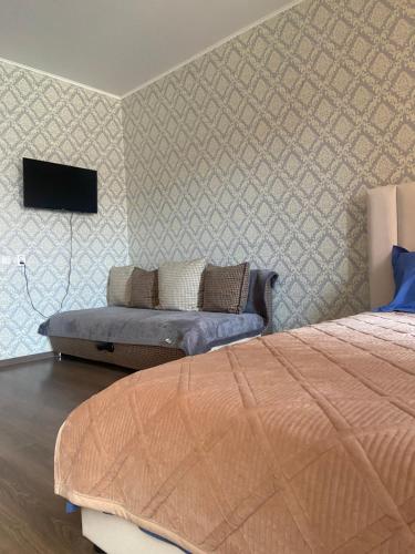 1 dormitorio con 1 cama y TV en la pared en Комфортабельные - Уютные апартаменты в Костанай Алтын Арман en Kostanái