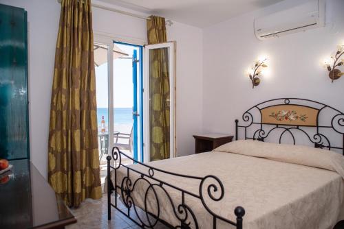 a bedroom with a bed and a balcony with the ocean at Deep Blue in Agios Prokopios