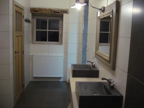 a bathroom with two sinks and a mirror and a window at La ferme Claudlisse in Vielsalm