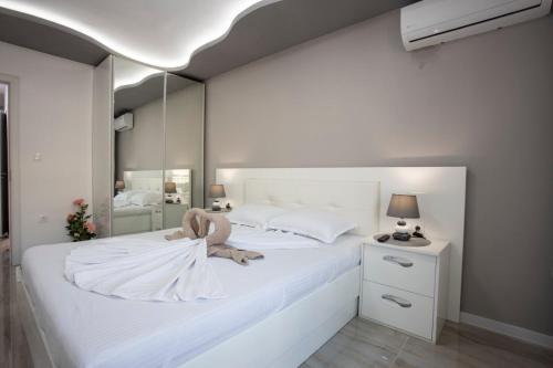 Un dormitorio con una cama blanca con un animal de peluche. en Апартамент за гости Ивви-1, en Burgas