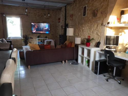 ein Wohnzimmer mit einem Sofa und einem TV in der Unterkunft Maison au Pied du Pont du Gard in Remoulins