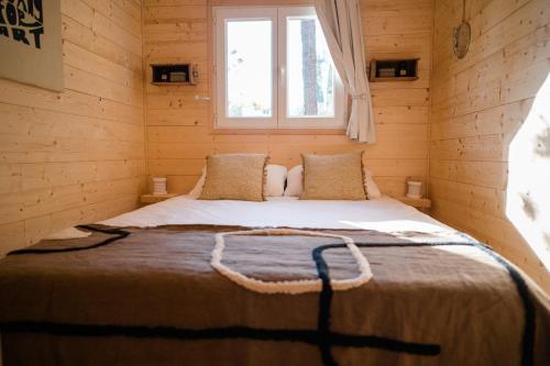 Ce lit se trouve dans une cabane en rondins dotée d'une fenêtre. dans l'établissement Les jardins de Manotte, à La Motte