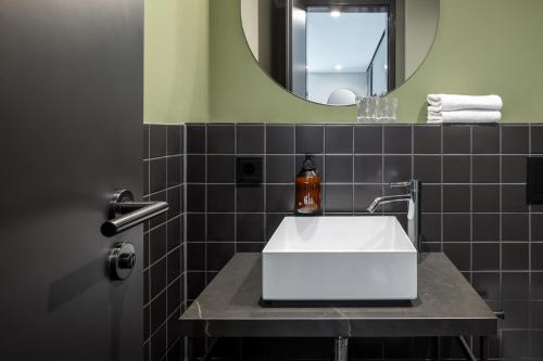 a bathroom with a white sink and a mirror at AMANO Home Leipzig in Leipzig