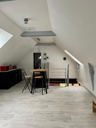 Cette chambre mansardée comprend une table et des chaises. dans l'établissement Appartement cosy à la campagne, à Languidic