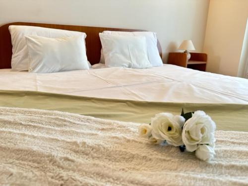a bed with white flowers on top of it at Cozy Garden Apartman in Gyula