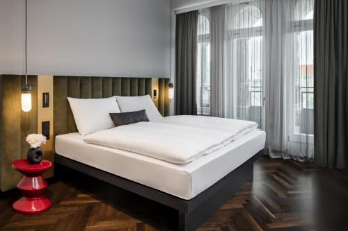 Un dormitorio con una gran cama blanca y una ventana en AMANO Home Leipzig en Leipzig