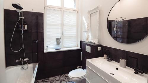 a bathroom with a tub and a toilet and a mirror at Grâce Boutique Apartments in Halle an der Saale
