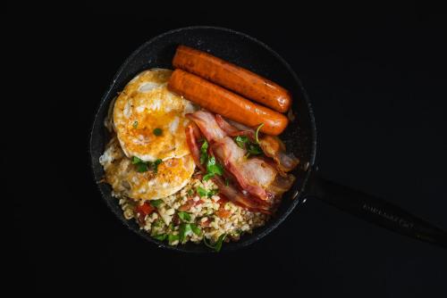 a pan of food with eggs bacon and carrots on risotto at Gravitas Hostel in Split