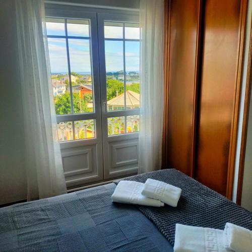 a bedroom with a bed and a window with a view at Rocas Brancas in Ribadeo