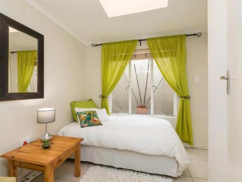 Schlafzimmer mit einem Bett und einem Fenster mit gelben Vorhängen in der Unterkunft Parkhurst Cottage in Johannesburg