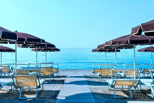 un grupo de sillas y sombrillas en una playa en Grand Hotel Pietra Ligure en Pietra Ligure