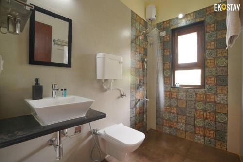 ein Bad mit einem Waschbecken, einem WC und einem Fenster in der Unterkunft EKOSTAY- Caribbean Villa in Panvel