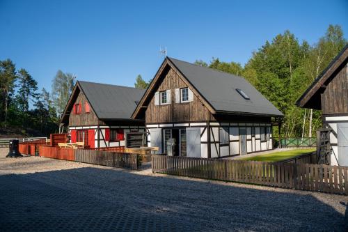 a house with a black roof and red and white at KOCANKA Domek w lesie, przy jeziorze w Kaszubskiej Wenecji, na Gwizdówce in Załakowo