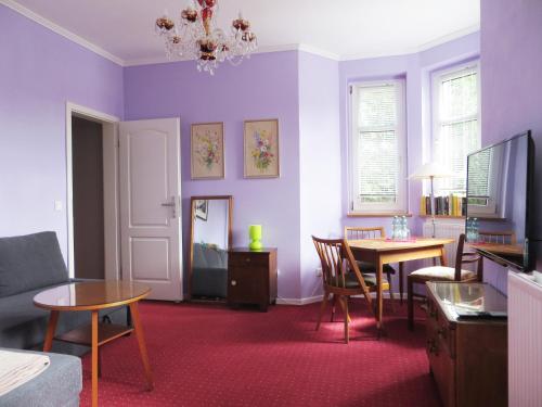 a living room with purple walls and a table and chairs at Die große Wohnung in Droyßig