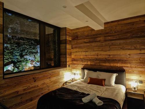 1 dormitorio con pared de madera, 1 cama y 2 lámparas en Le Enecy - Spa - Cœur Vieille ville, en Annecy