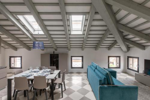 una sala da pranzo con tavolo, sedie e finestre di Corte alle mura - Mansarda lux a Cittadella